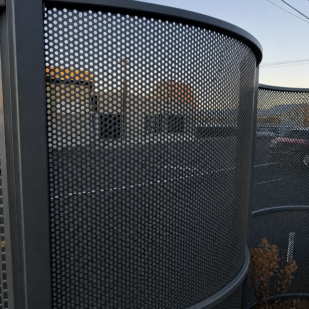 Curved black perforated metal screen panels for an architectural facade