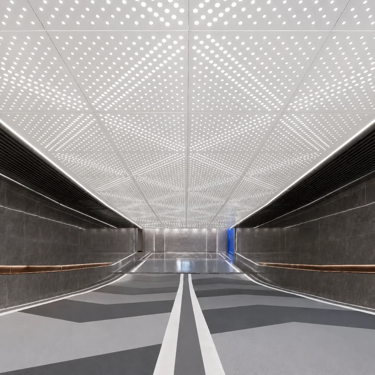 White perforated metal acoustic ceiling panels with round holes in a commercial corridor