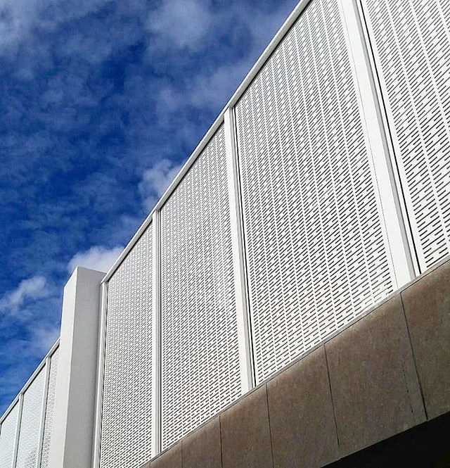 White slotted perforated metal cladding panels on a building facade