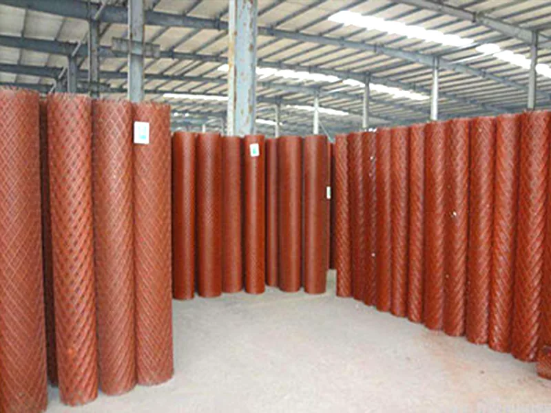 Red expanded metal mesh rolls stored in a production warehouse