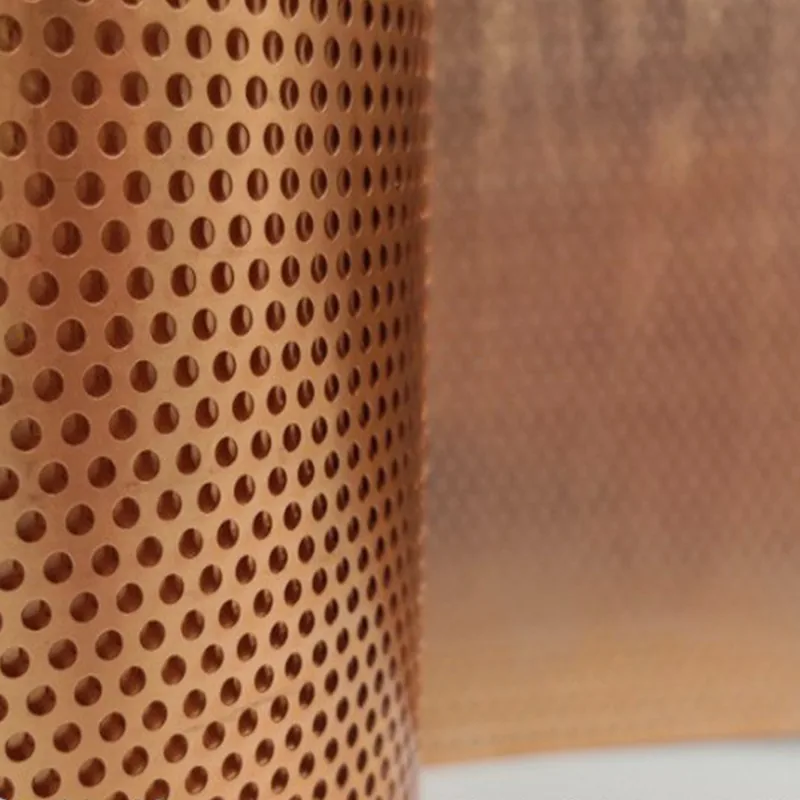 Copper perforated metal sheet close-up with staggered round holes