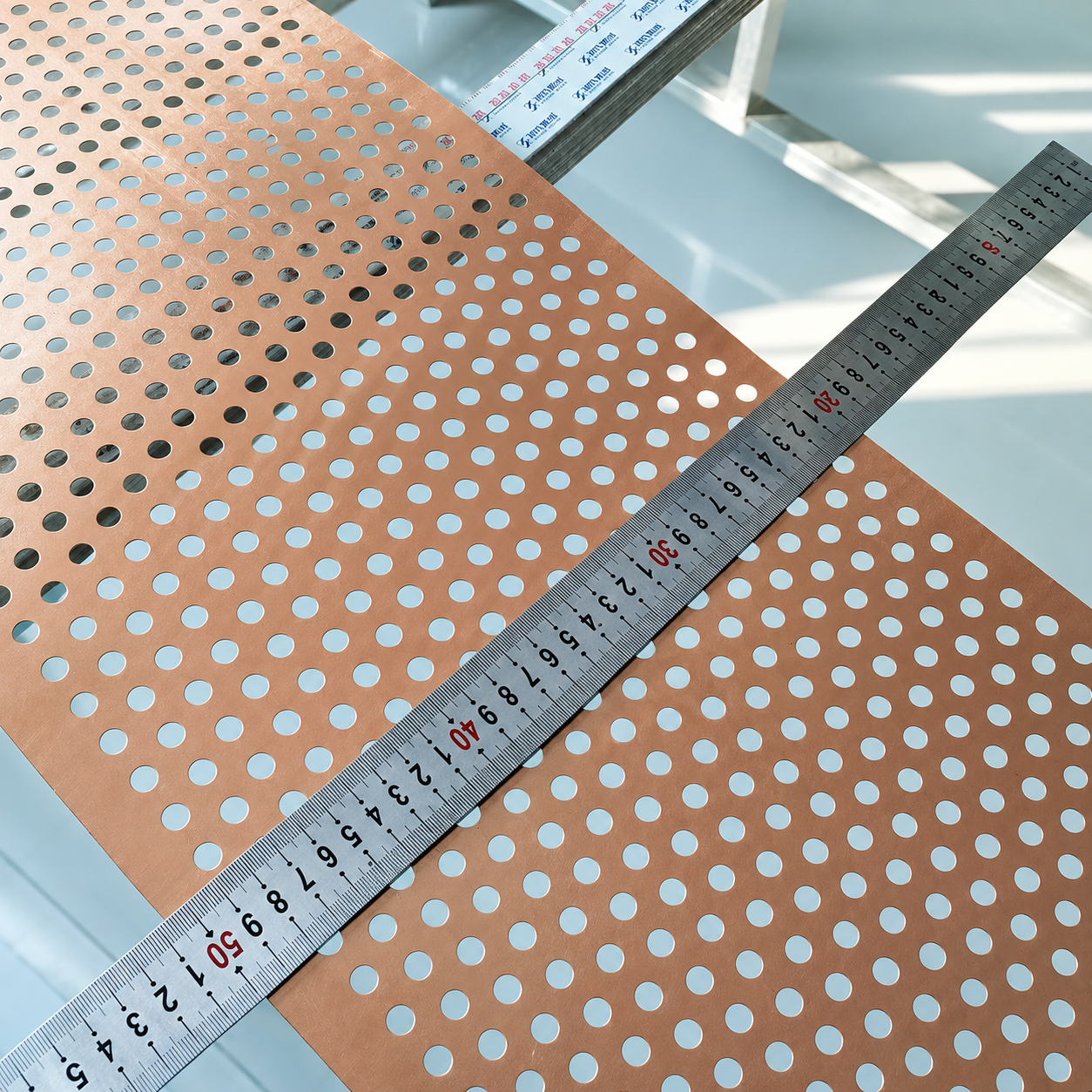Copper perforated sheet with round holes and measurement ruler for custom specification review