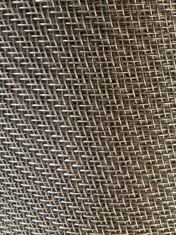 Close-up of stainless steel twill weave mesh showing overlapping wires and staggered intersections