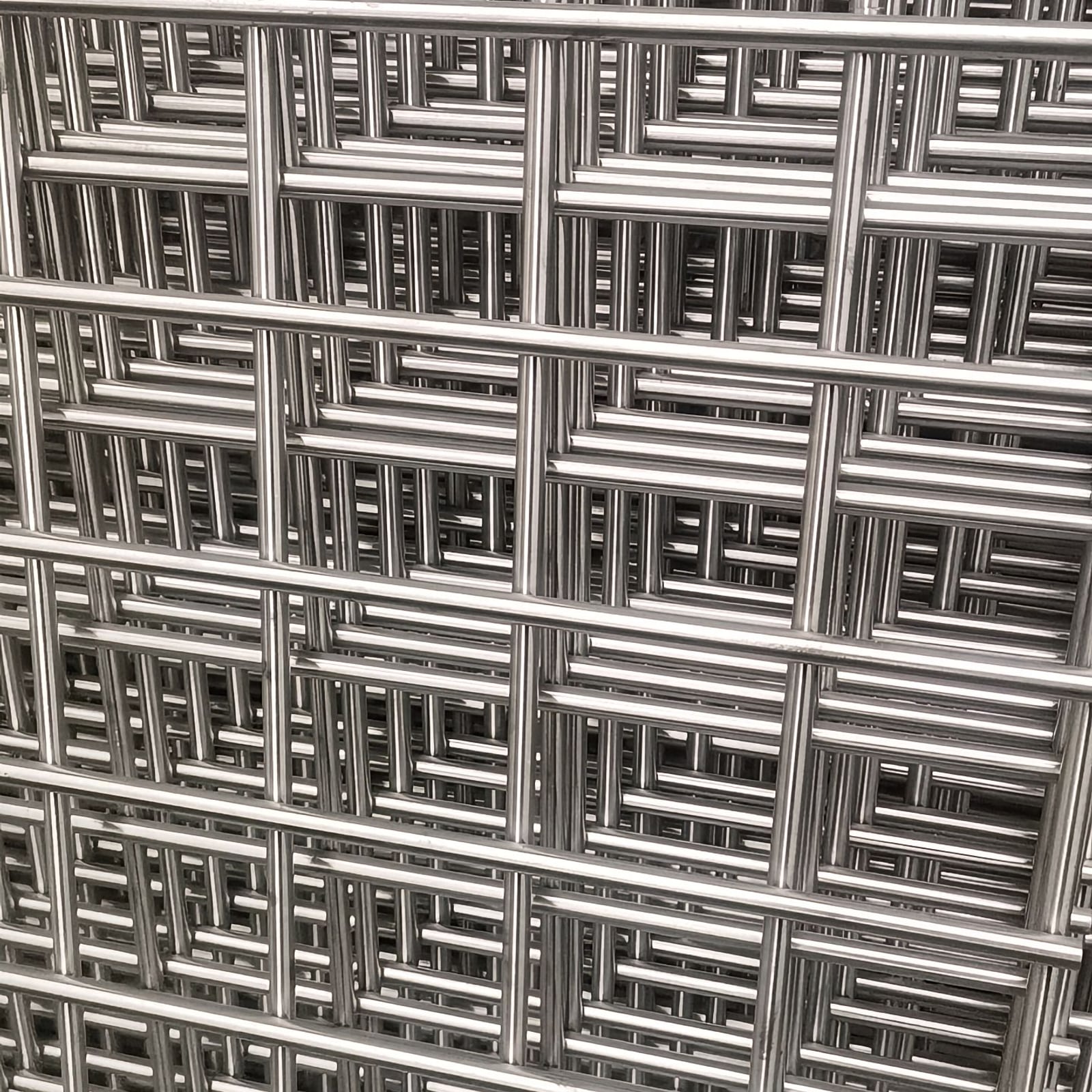 Close-up of stacked stainless steel welded wire mesh panels with repeated rectangular openings